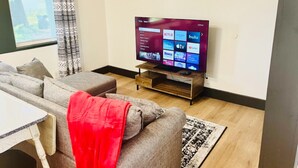A living room with a sofa, a coffee table, and a flat-screen TV displaying streaming services. - Little Red Loft | Cozy Guest Suite Apartment (Danville)
