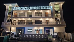 Een meerlaags hotel met een opvallend “WHITEHOUSE” bord, balkons en een goed verlichte gevel.