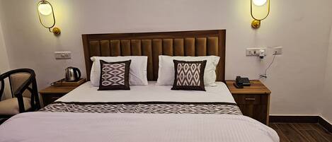 A hotel room with a large bed, two bedside tables, a wooden headboard, and two wall-mounted lights.