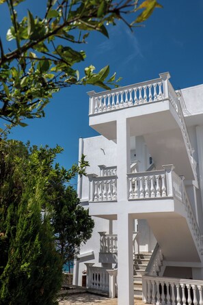 A white multi-story building with balconies and a staircase. - Hotel Horizon Ksamil (Ksamil)