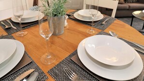 A dining table set with plates, glasses, and cutlery, surrounded by a cozy living area with a couch and decorative items. - Troon House - East Kilbride (Glasgow)