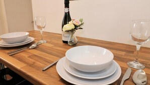 Uma mesa de jantar com pratos brancos, uma garrafa de vinho e um vaso com flores.