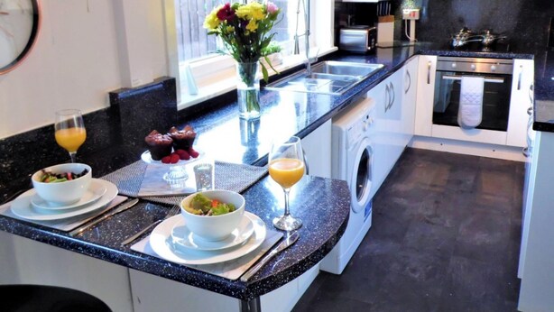 A modern kitchen with a central island, built-in appliances, and a window with a view. - Stanefield House Motherwell (Motherwell)