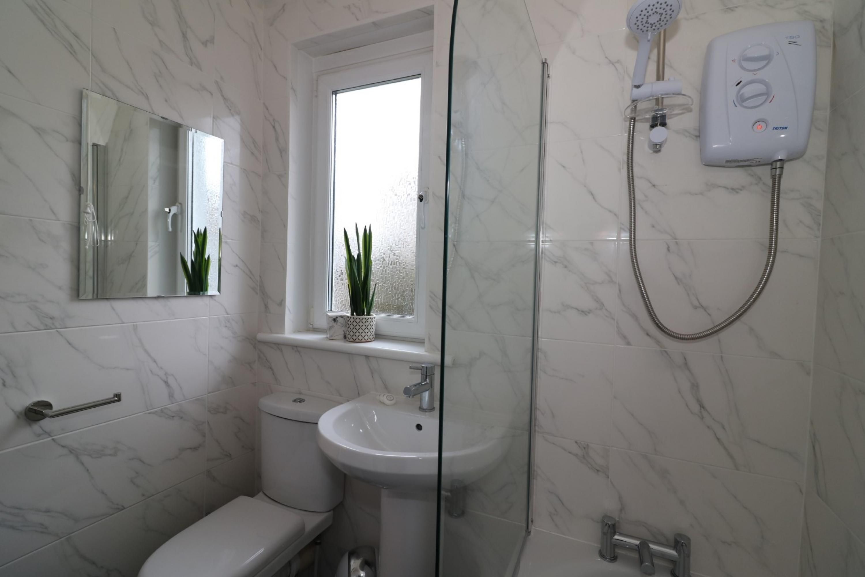 A bathroom with a toilet, sink, and shower.
