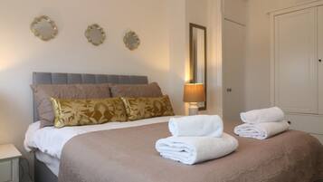 Una habitación de hotel con una cama, una mesita de noche, una lámpara y un armario.