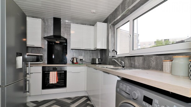 A modern kitchen with a built-in oven, microwave, and washing machine.