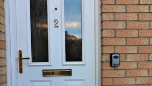 A white door with a brass handle, a glass panel, and the number 2. There are two mailboxes on the brick wall beside the door. - Connelly House - Motherwell (Motherwell)