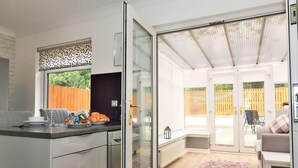 Een moderne keuken met een schuifdeur naar een patio met een houten terras en tuinmeubilair.