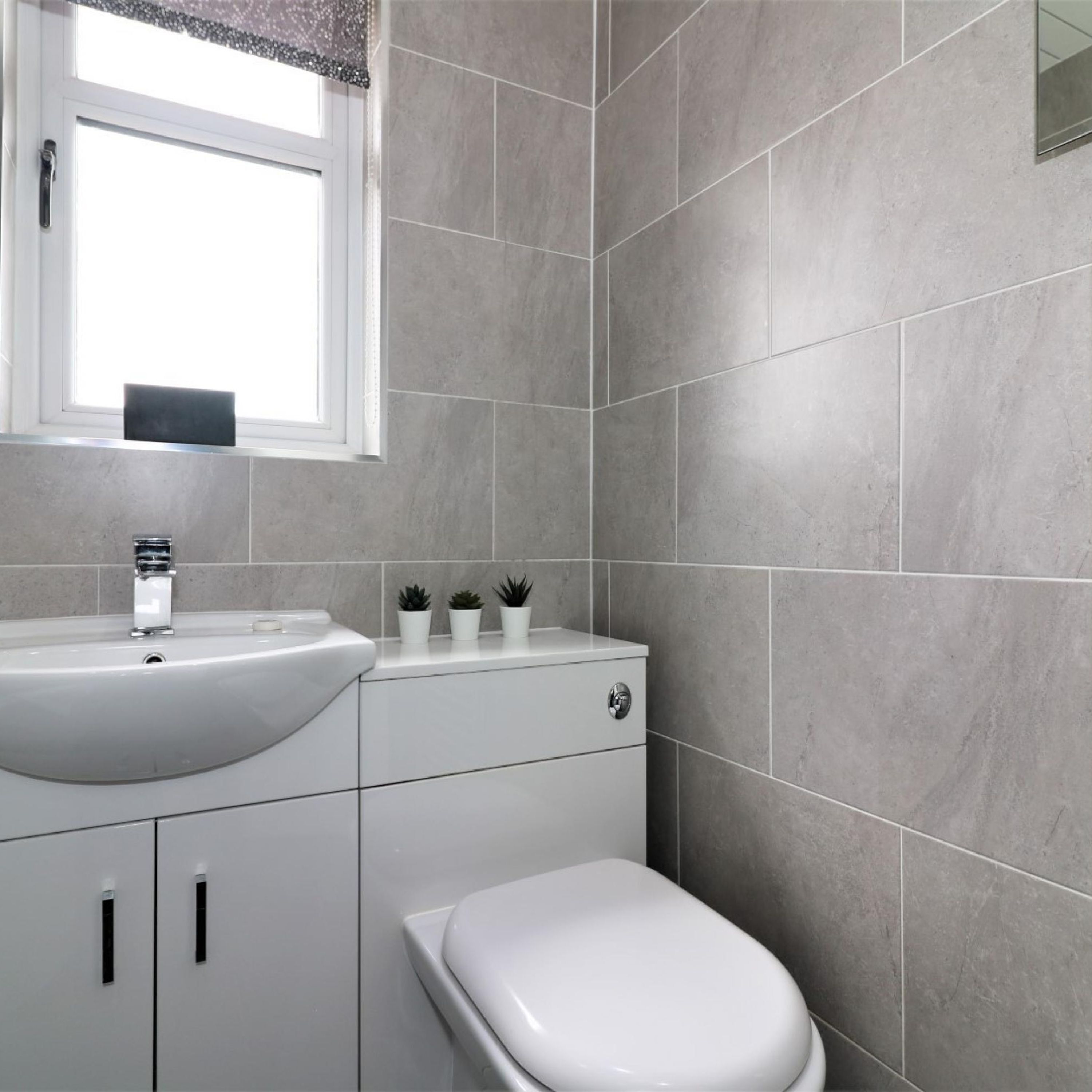 A bathroom with a white sink, a toilet, and a window above the sink.
