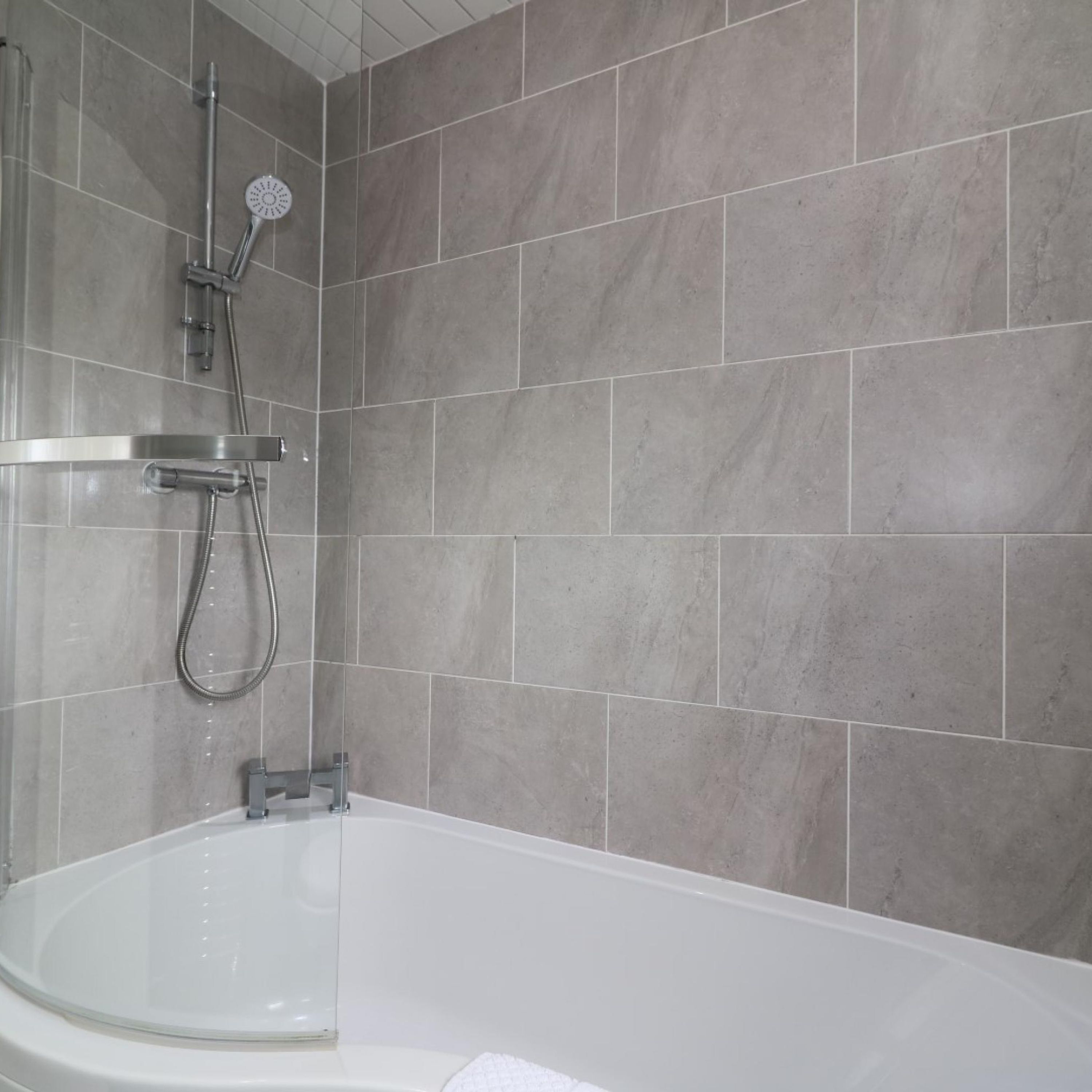 A modern bathroom with a bathtub, a shower with a handheld showerhead, and a wall-mounted faucet.