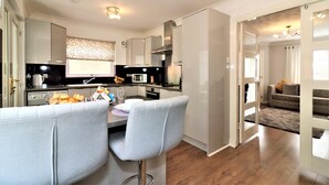Een moderne keuken met een eetgedeelte, met een centraal eiland, inbouwapparatuur en uitzicht op de woonkamer.