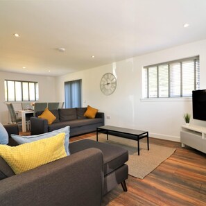 A modern living room with a sofa, coffee table, and a TV. - Railway House 5 bed - Maryhill (Glasgow)