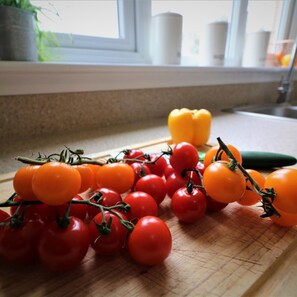 Eine Küchenarbeitsplatte mit Schneidebrett, belegt mit Kirschtomaten und einer gelben Paprika.