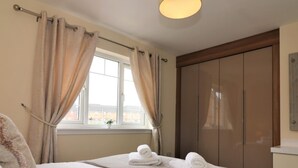Un dormitorio con cama, cortinas, ventana y armario.