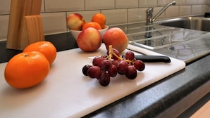 A kitchen counter with a cutting board, a bowl of fruit, and a knife block. - Belhaven House - Hamilton (Hamilton)
