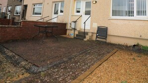 A residential building with a brick patio, a metal table, and a chair. - Atholl House - Linwood (Paisley)