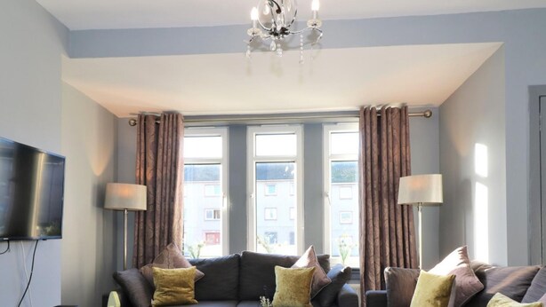 Een moderne woonkamer met een bank, twee fauteuils, een salontafel en een televisie.