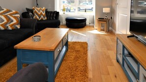 Ein modernes Wohnzimmer mit einer Couch, einem Couchtisch und einem Fernseher.