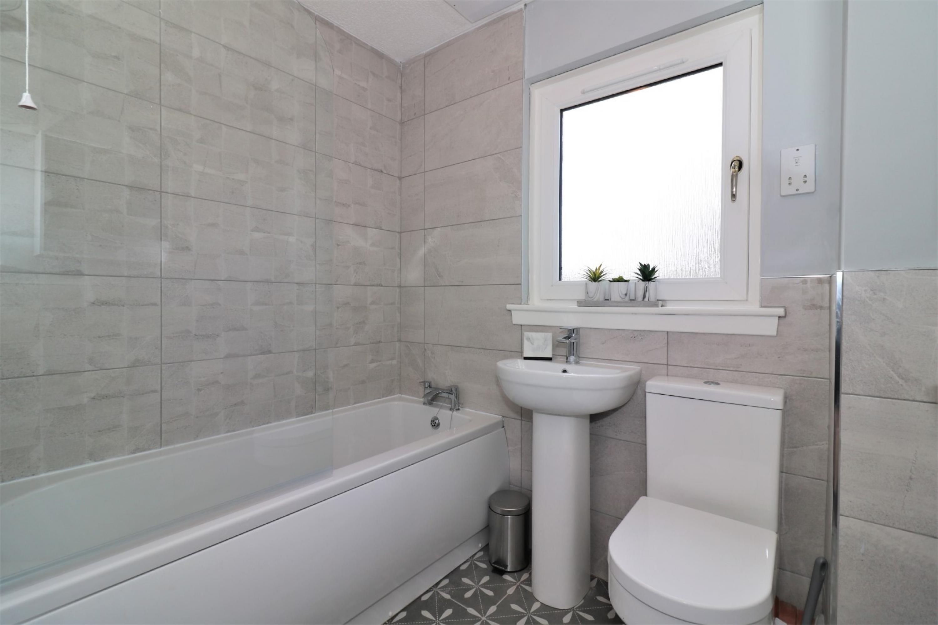 A modern bathroom with a bathtub, sink, and toilet.