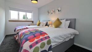 Een slaapkamer met twee bedden, een raam en kunst aan de muur.