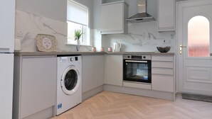 Een moderne keuken met een inbouw wasmachine, oven en een raam dat voor natuurlijk licht zorgt.