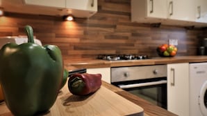 Una cocina con armarios de madera, tabla de cortar y un pimiento rojo y verde.