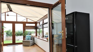 Una habitación con puerta de vidrio corredera que da a un patio, un refrigerador negro y piso de madera.