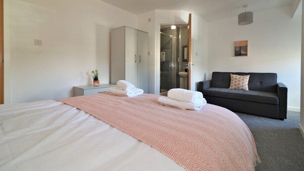 Ein modernes Hotelzimmer mit einem großen Bett, einer Couch, einem kleinen Tisch und einem Spiegel.