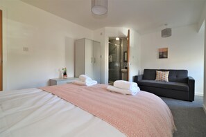 A modern hotel room with a large bed, a sofa, a small table, and a mirror. - Great Western View - Glasgow (Glasgow)