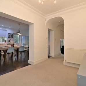 A spacious kitchen with modern appliances, a dining area with chairs, and a hallway leading to another room.