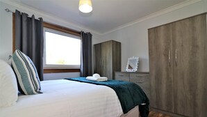 A bedroom with a bed, a wardrobe, a dresser, and a window with curtains. - Dumbreck House - Glasgow (Glasgow)