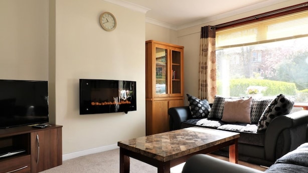 A living room with a flat-screen TV, a wooden cabinet, a sofa, and a coffee table. - Dumbreck House - Glasgow (Glasgow)
