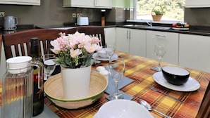 A modern kitchen with white cabinets, a skylight, and a dining area set with a plaid tablecloth, plates, and glasses. - Dumbreck House - Glasgow (Glasgow)