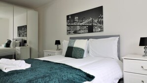 A modern bedroom with a large bed, a cityscape painting, a nightstand, and a wardrobe. - Kirkhill Middle - Lanark (Lanark)