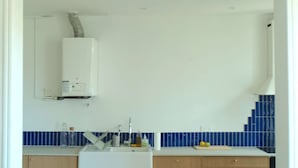 Une cuisine moderne avec un évier blanc, des armoires en bois et un dosseret carrelé de couleur bleue.
