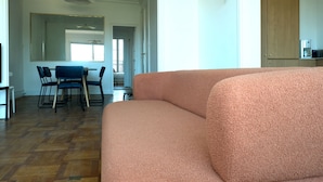Un salon avec un canapé, une table à manger avec des chaises et un coin cuisine avec des placards.