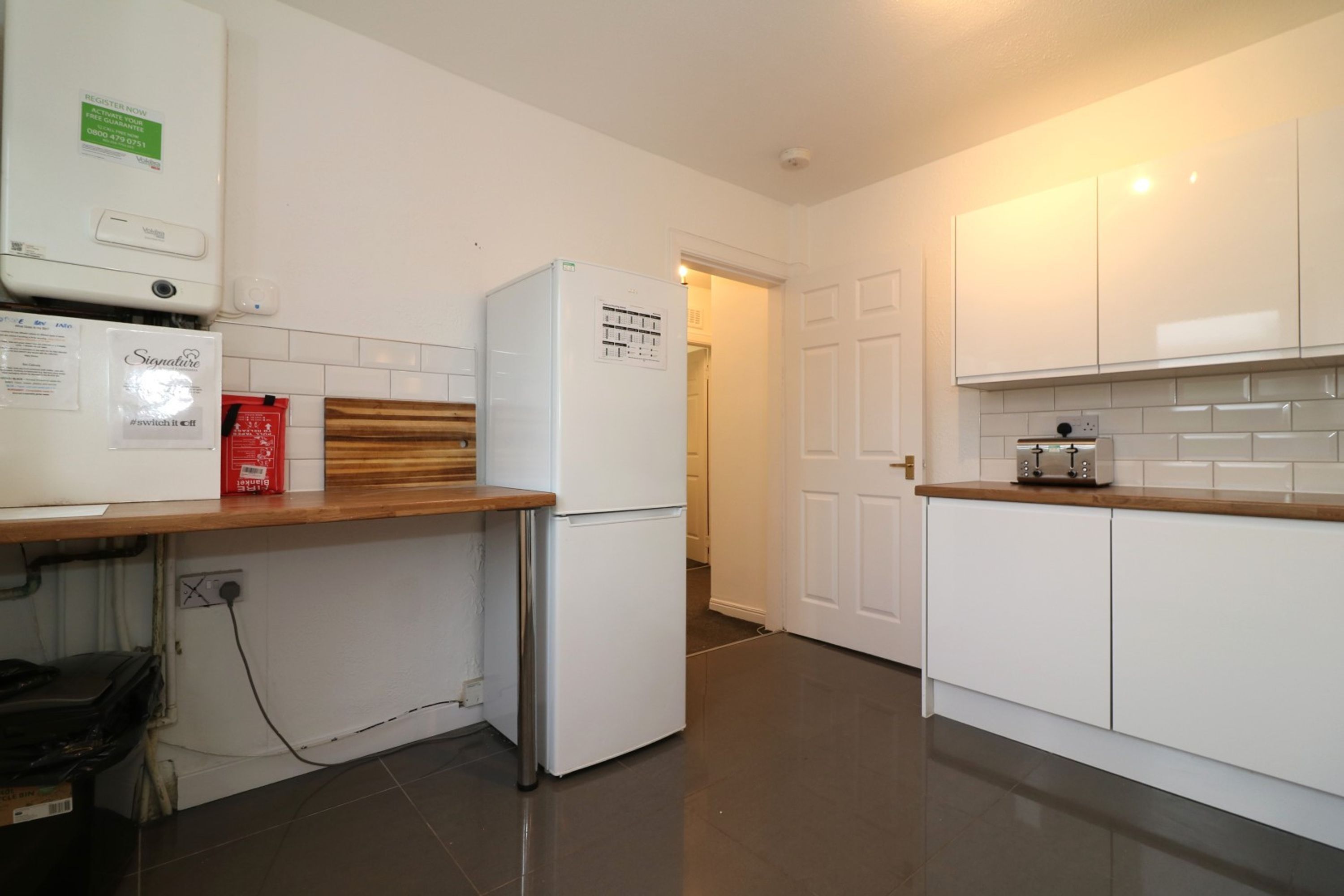 A modern kitchen with white cabinets, a built-in oven, and a countertop with a toaster.