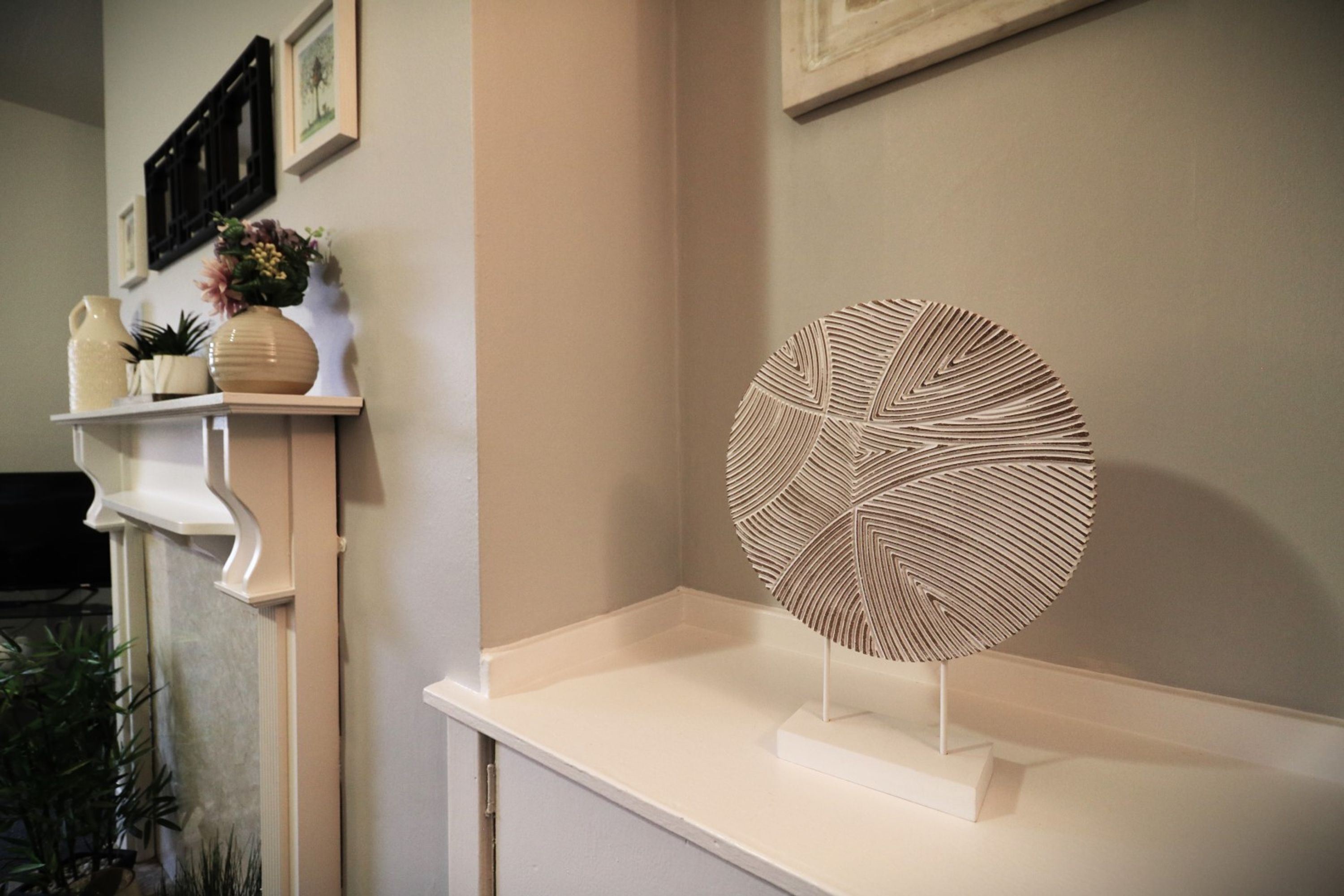 A white shelf with decorative items and a geometric art piece.