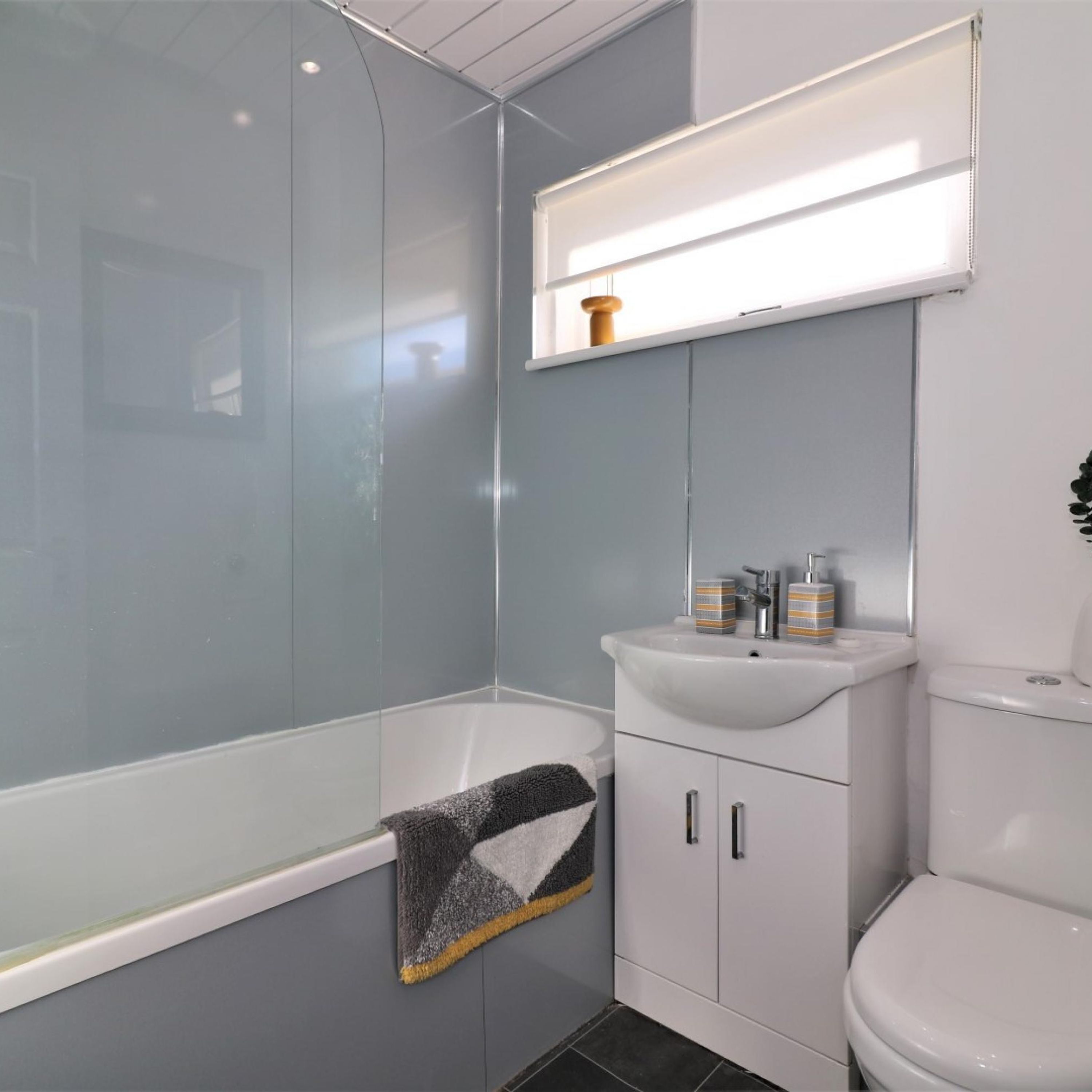 A modern bathroom with a glass shower enclosure, a white sink with striped soap dispensers, and a toilet.