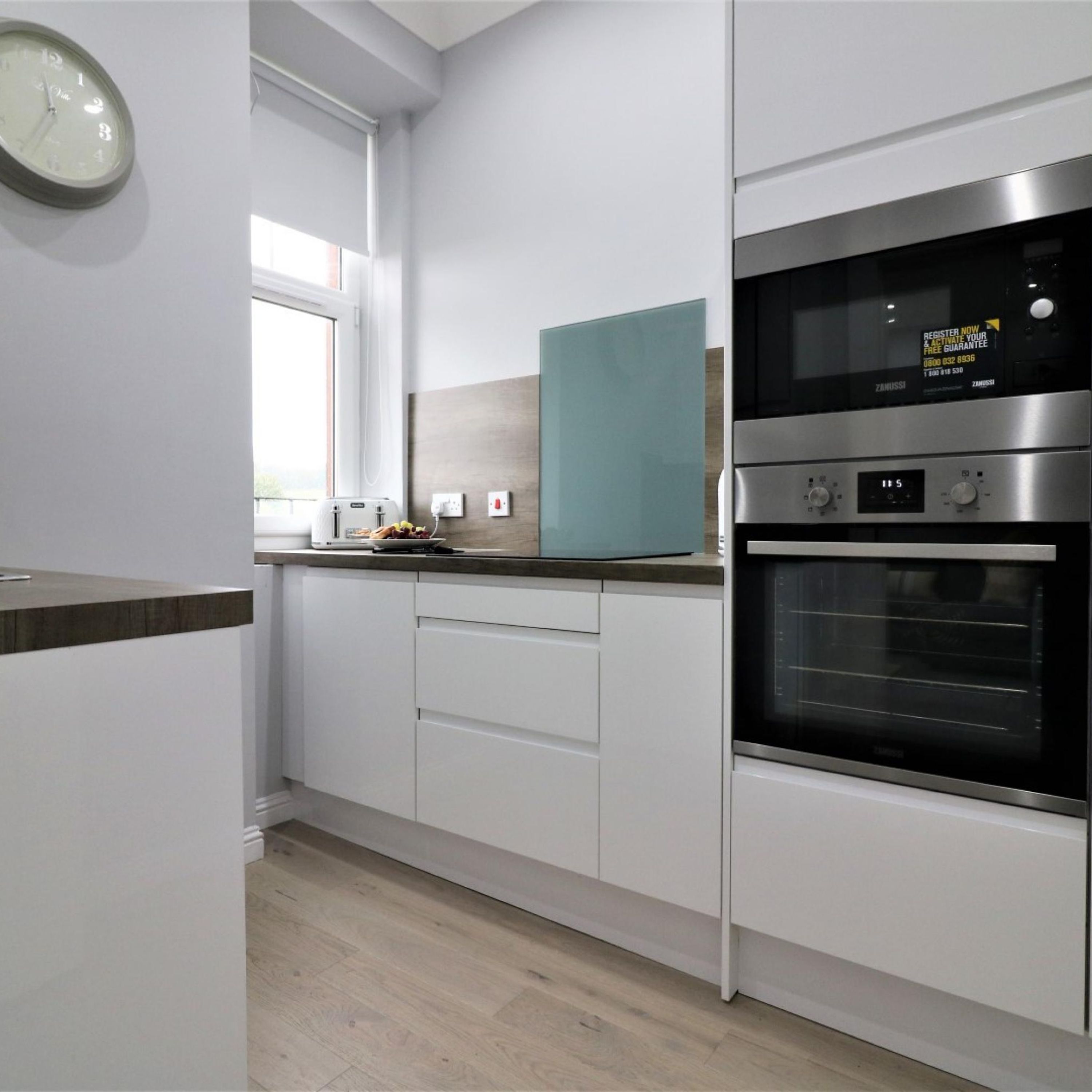 Eine moderne Küche mit weißen Schränken, einer eingebauten Mikrowelle und einem Backofen.