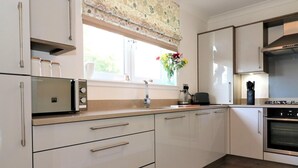 Eine moderne Küche mit weißen Schränken, einem eingebauten Backofen und einem Fenster mit einem blumigen Vorhang.