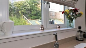Eine Küche mit Fenster, Spüle, Wasserkocher und einer Blumenvase.