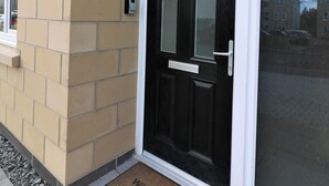Eine schwarze Tür mit der Nummer 5, ein Briefkasten und ein kleines Fenster an der Wand.