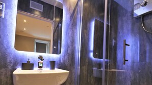 Une salle de bain moderne avec un lavabo sur colonne, un grand miroir et une douche séparée par des parois en verre.