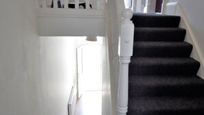 Un escalier avec des marches recouvertes d’une moquette sombre et des balustrades blanches.