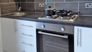Une cuisine moderne avec des meubles blancs, un plan de travail noir, une cuisinière et un four.