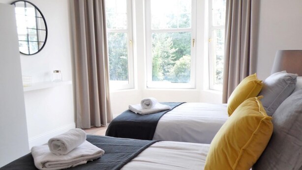 Une chambre d’hôtel avec deux lits, une fenêtre et une vue sur les arbres.