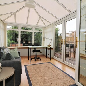 A conservatory with a desk, chair, and a sofa.