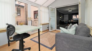 Ein großzügiger Wohnbereich mit Esstisch, grauem Sofa und großem Fenster.