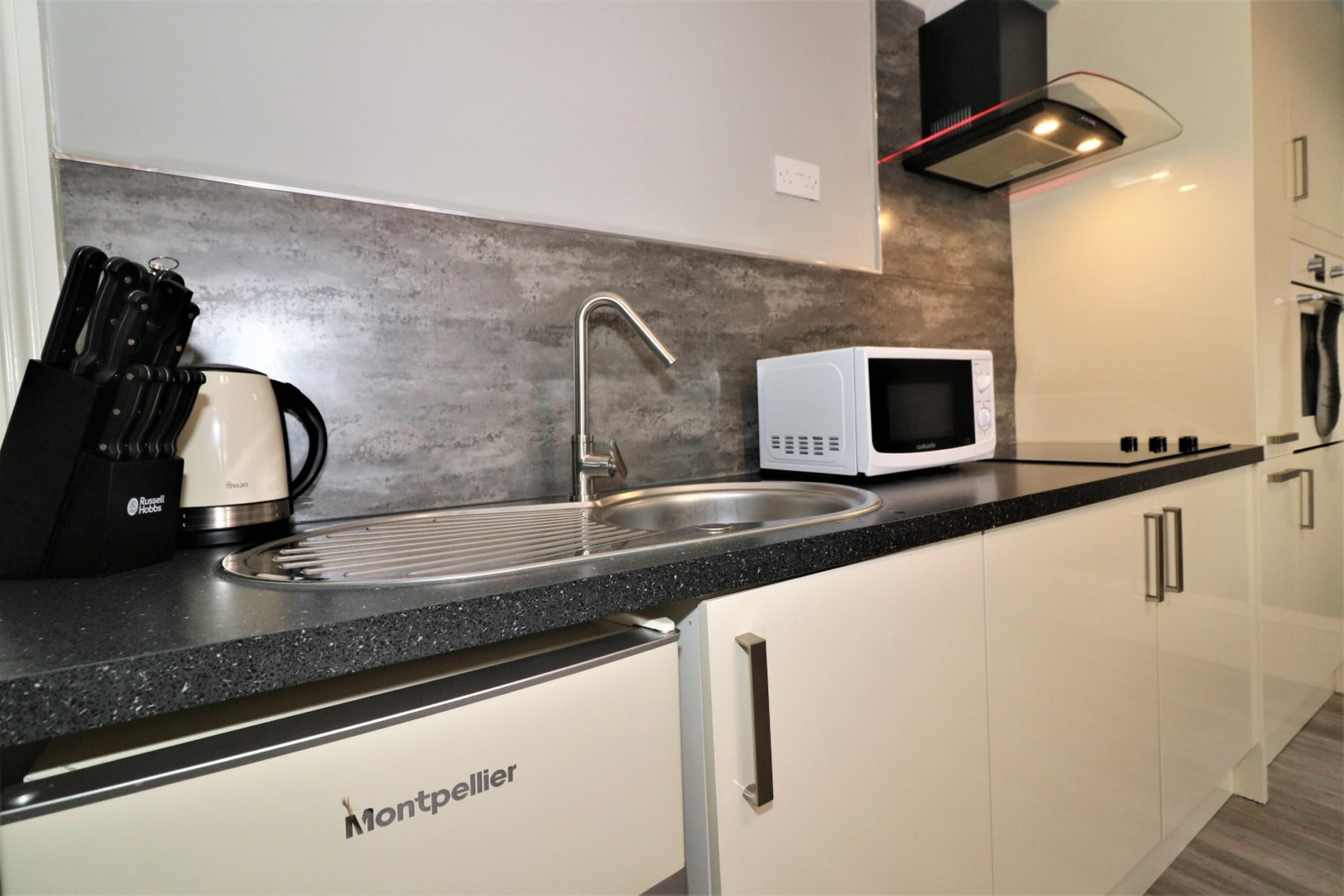 A modern kitchen with a stainless steel sink, a microwave, and a coffee maker.
